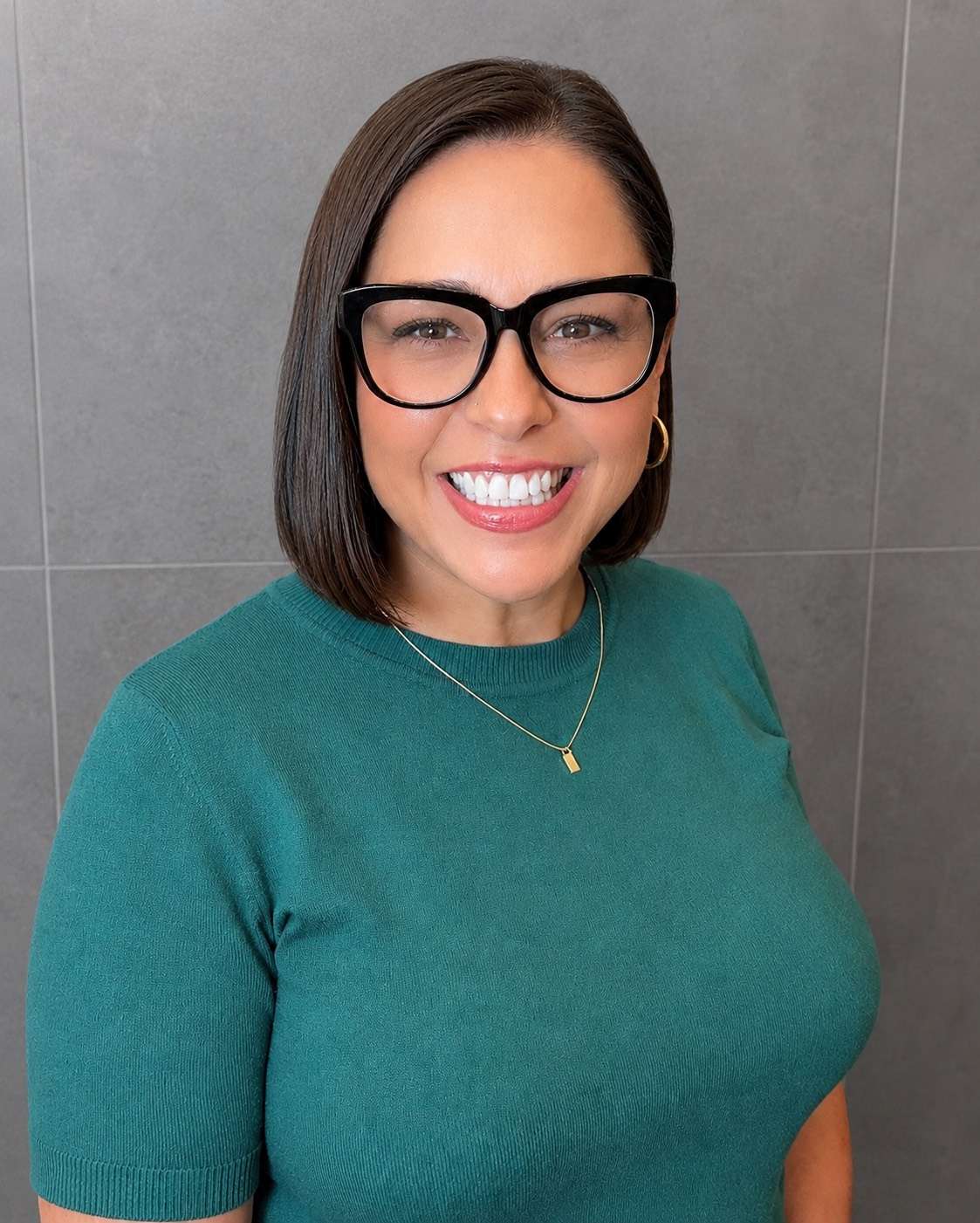 Bobbie Hotler with shoulder-length brown hair smiles, wearing a patterned top and necklace.