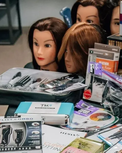 Mannequin heads with brown hair surrounded by hair styling tools and supplies.