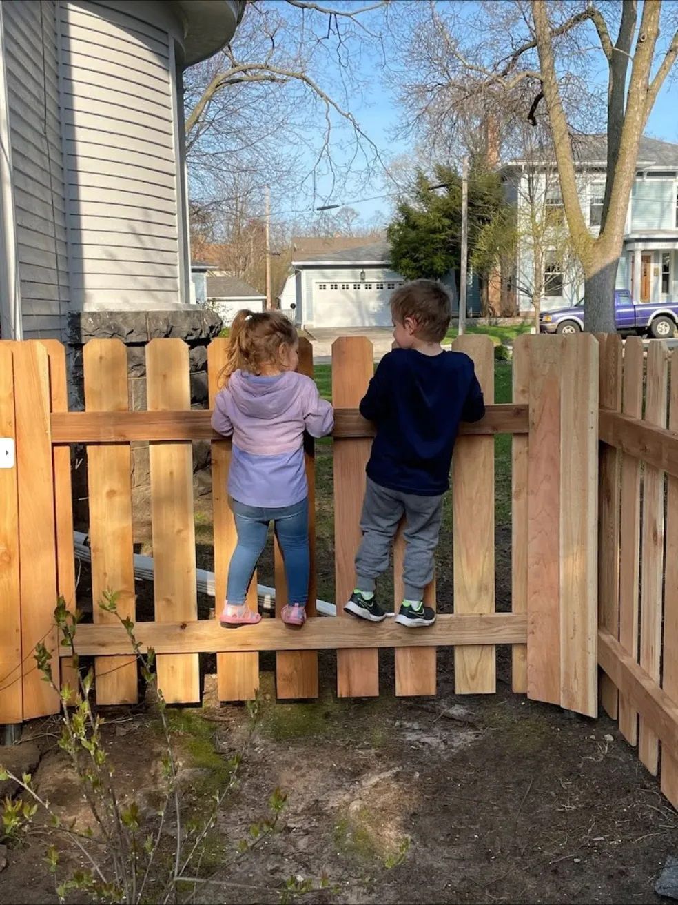 2 children on wooden fence