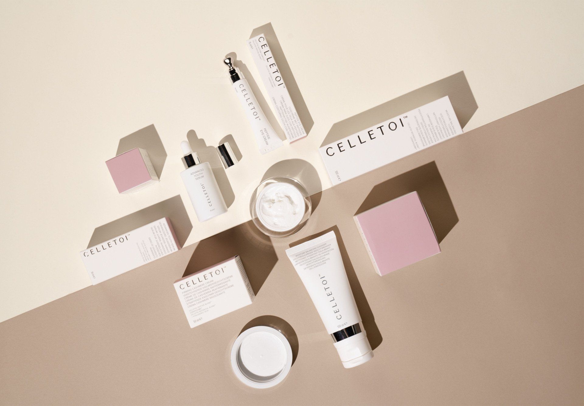 Skincare products arranged on a beige and white surface with shadows, including a jar of cream and a tube.