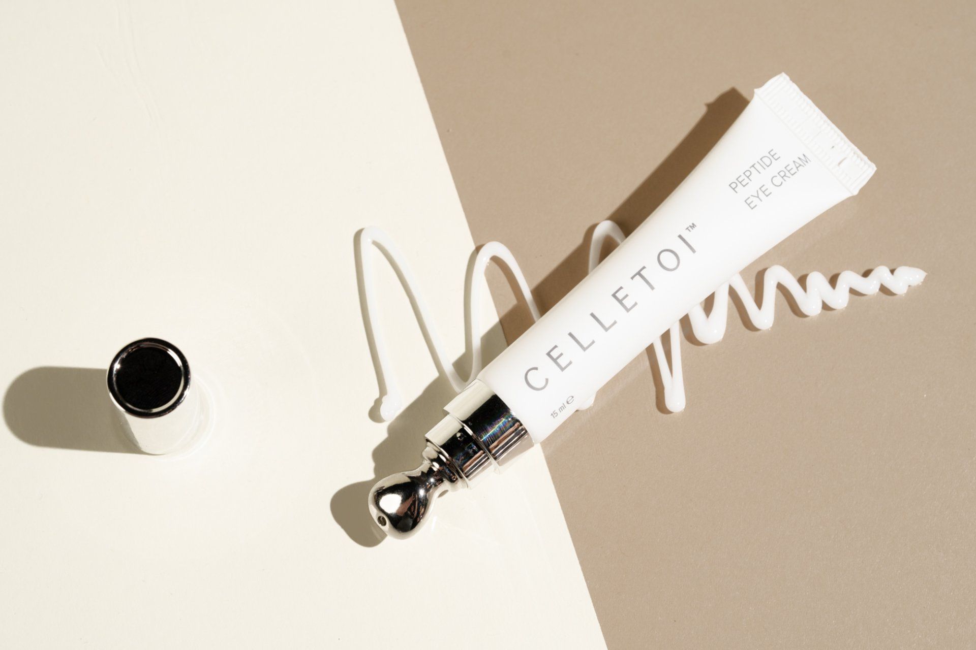 Celletoi peptide eye cream tube with applicator, cream swirl on neutral background.