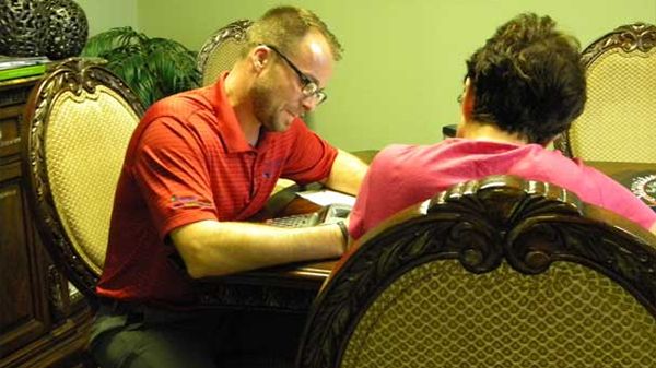 A man in a red shirt is sitting at a table with a woman in a pink shirt.