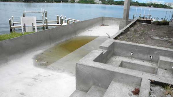 A concrete pool is being built next to a body of water.