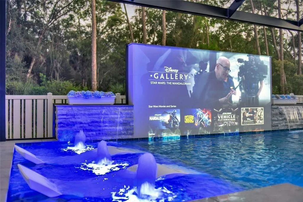 A large screen is projected on a wall over a swimming pool.