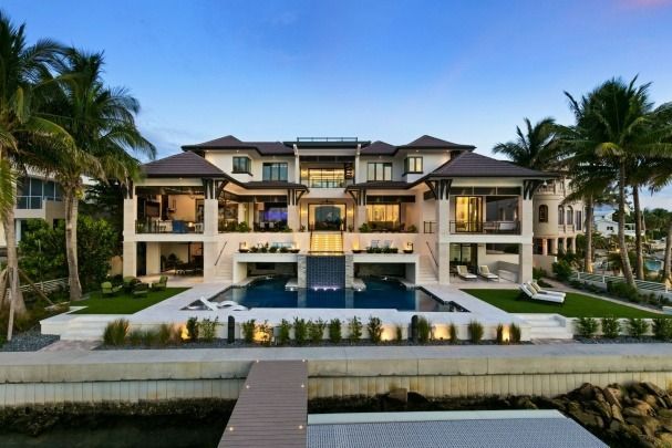 A large house with a swimming pool is surrounded by palm trees