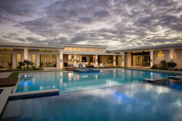 A large swimming pool in front of a house with a cloudy sky in the background.