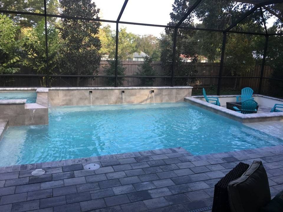 A large swimming pool is surrounded by a screened in area.