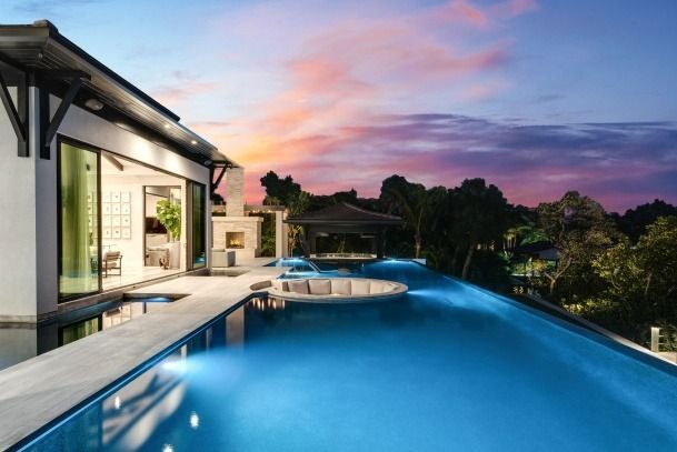 A large swimming pool in front of a house at sunset