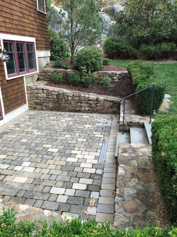 A brick patio with stairs leading up to it next to a house.