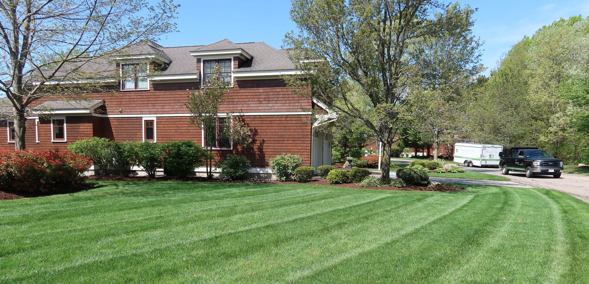 A large brick house with a lush green lawn in front of it.