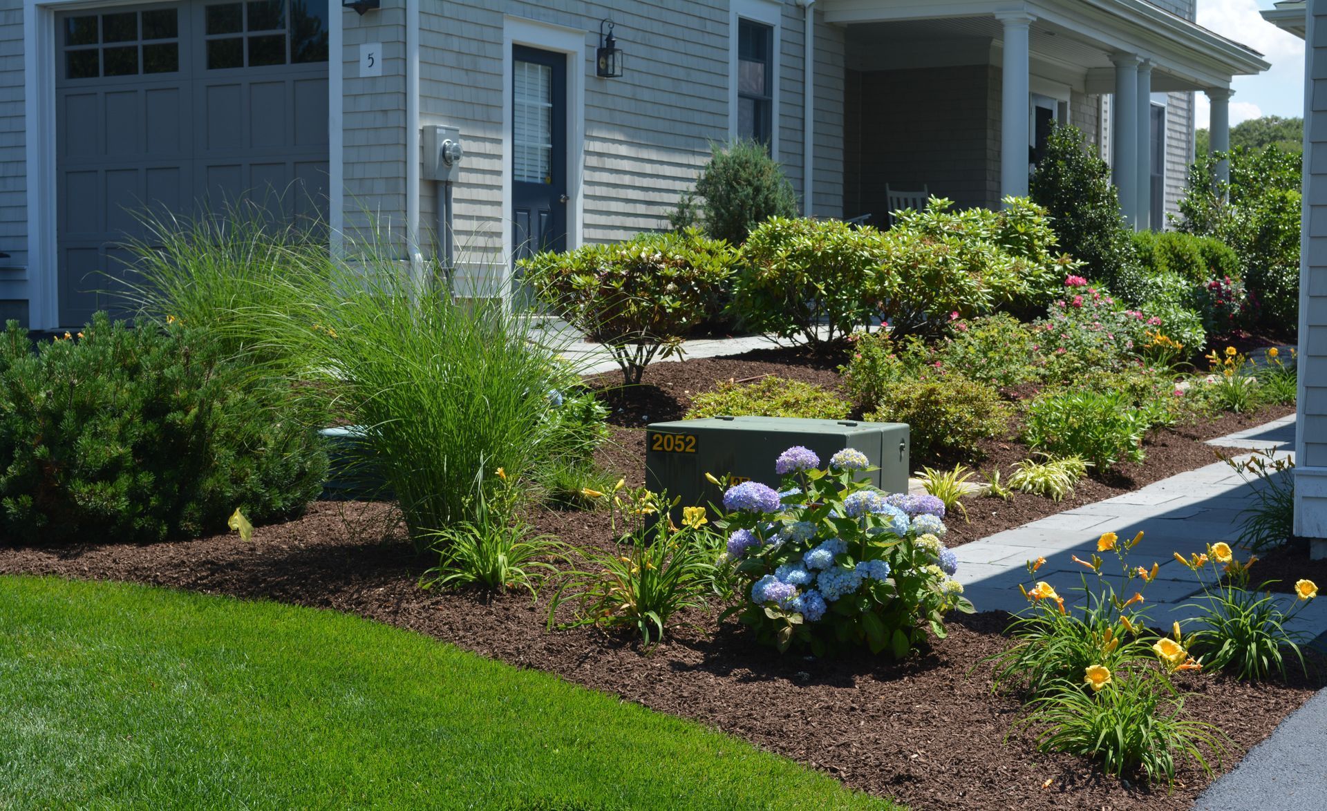 A house with a lot of plants and flowers in front of it.
