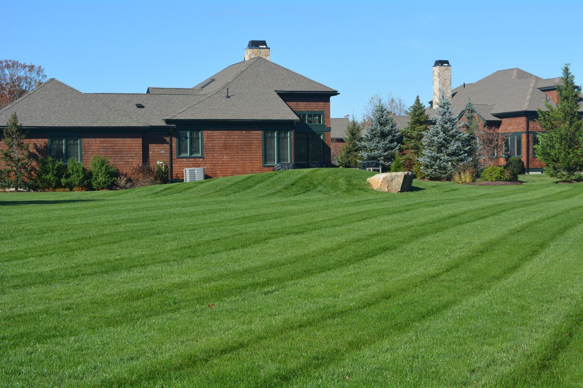 A spacious brick house with a vibrant green lawn stretching out in front.