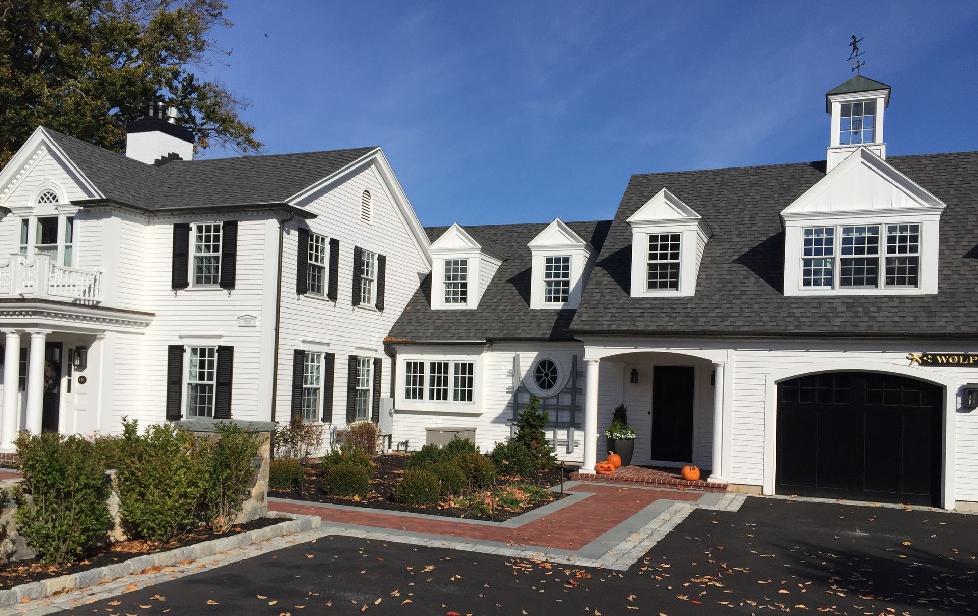 A large white house with a gray roof and black shutters.