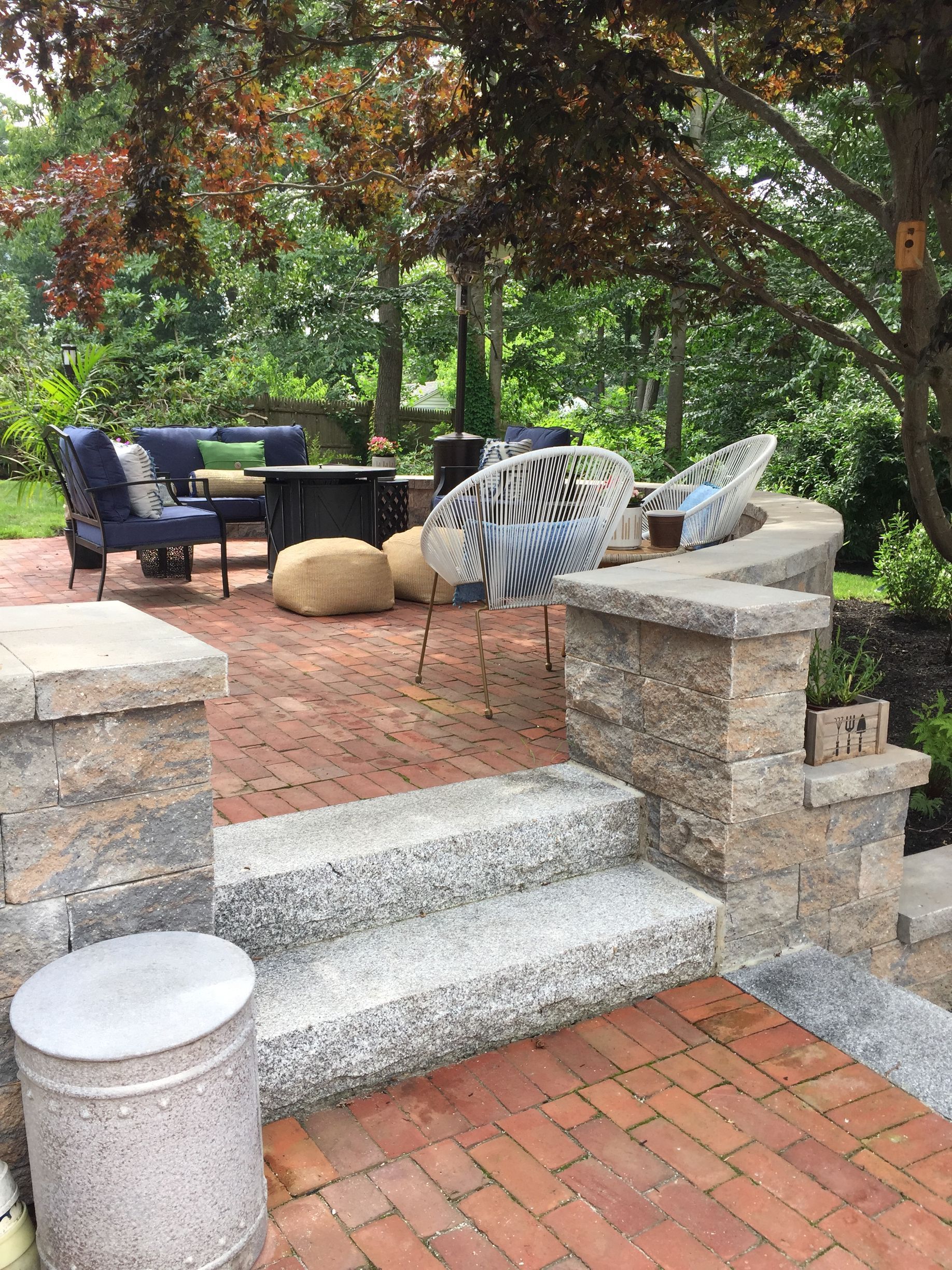 A brick patio with stairs leading up to a table and chairs.