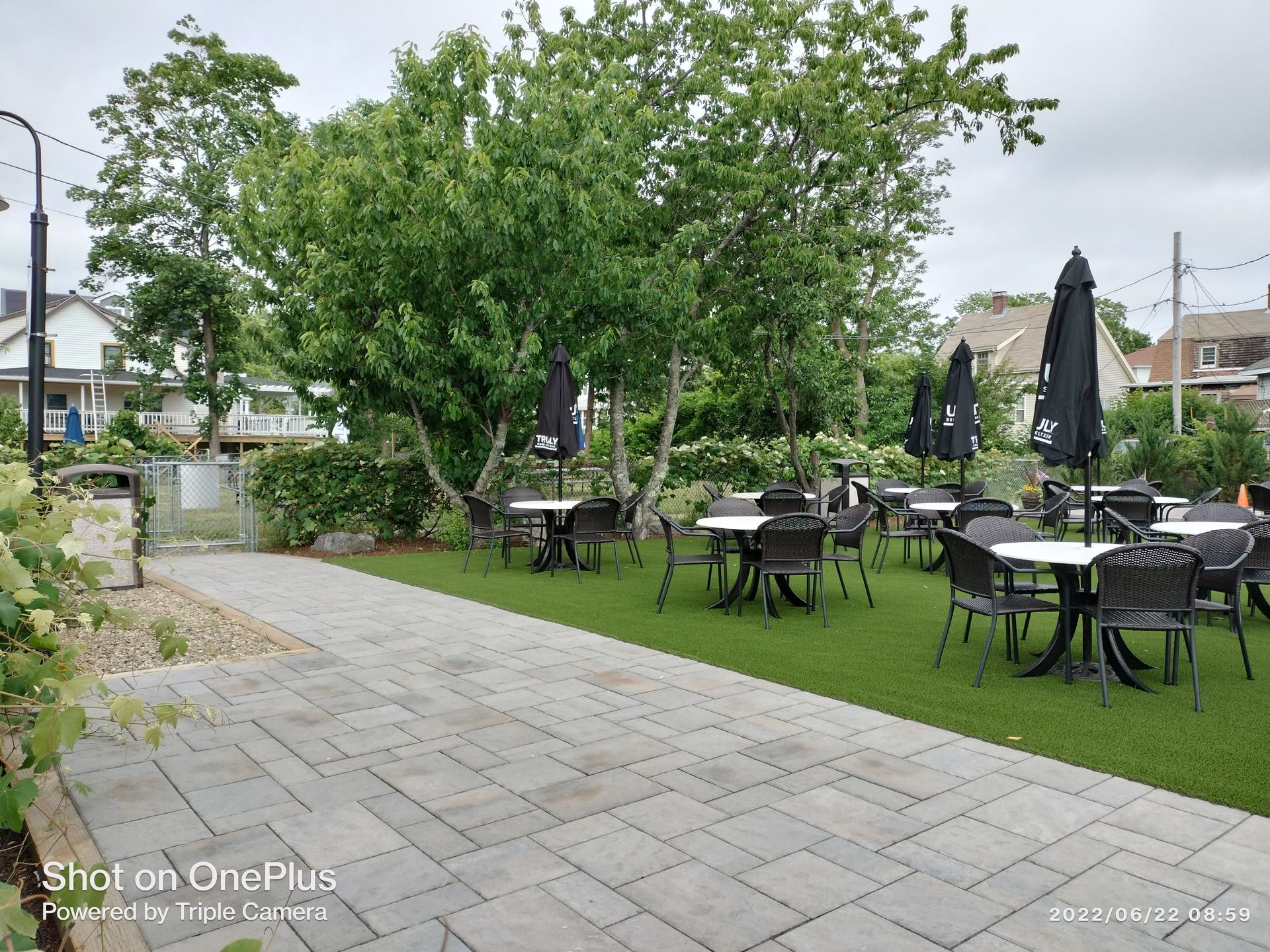 A patio with tables and chairs and umbrellas in a park.