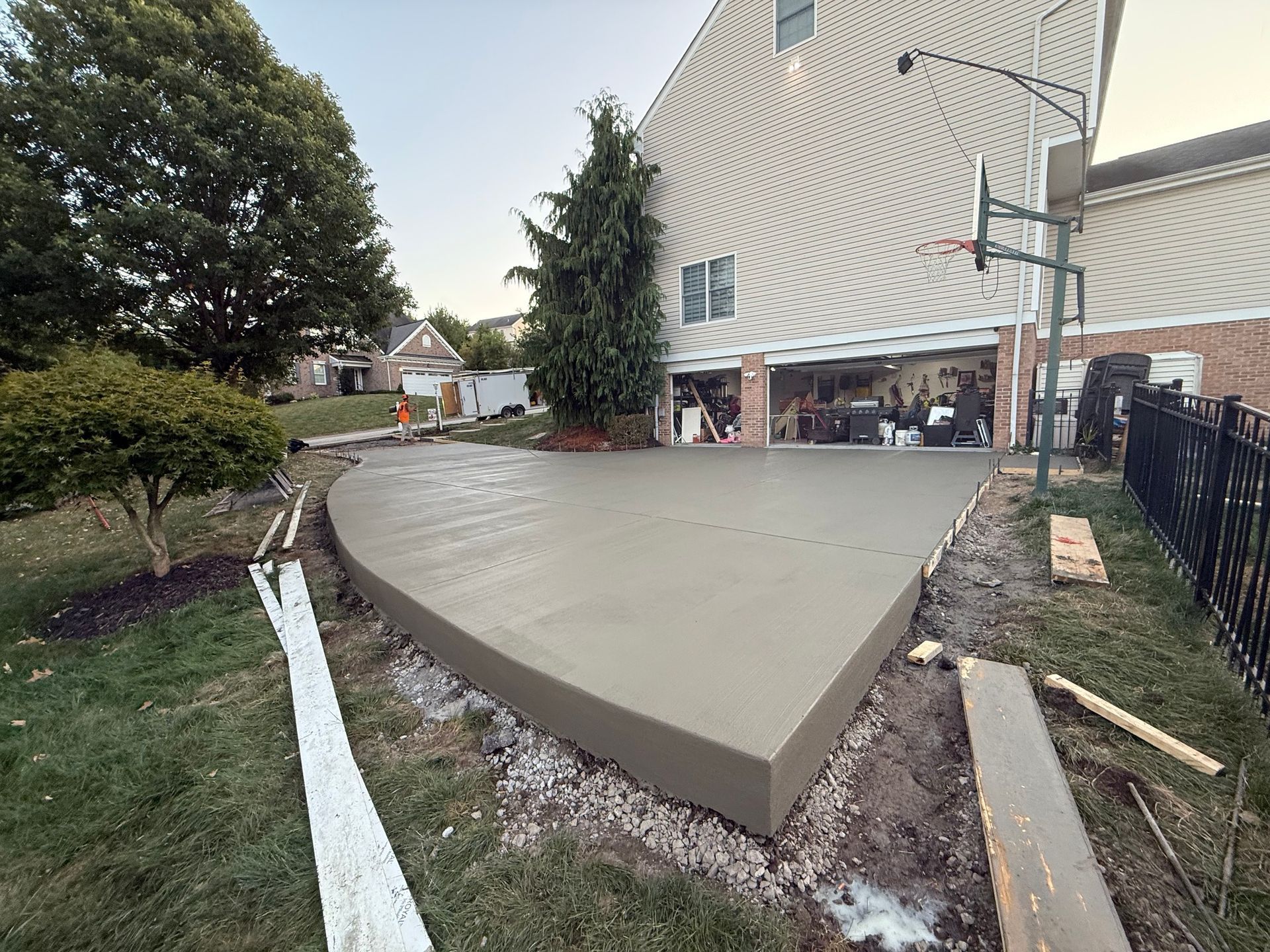 Newly poured concrete patio next to a house with a basketball hoop.