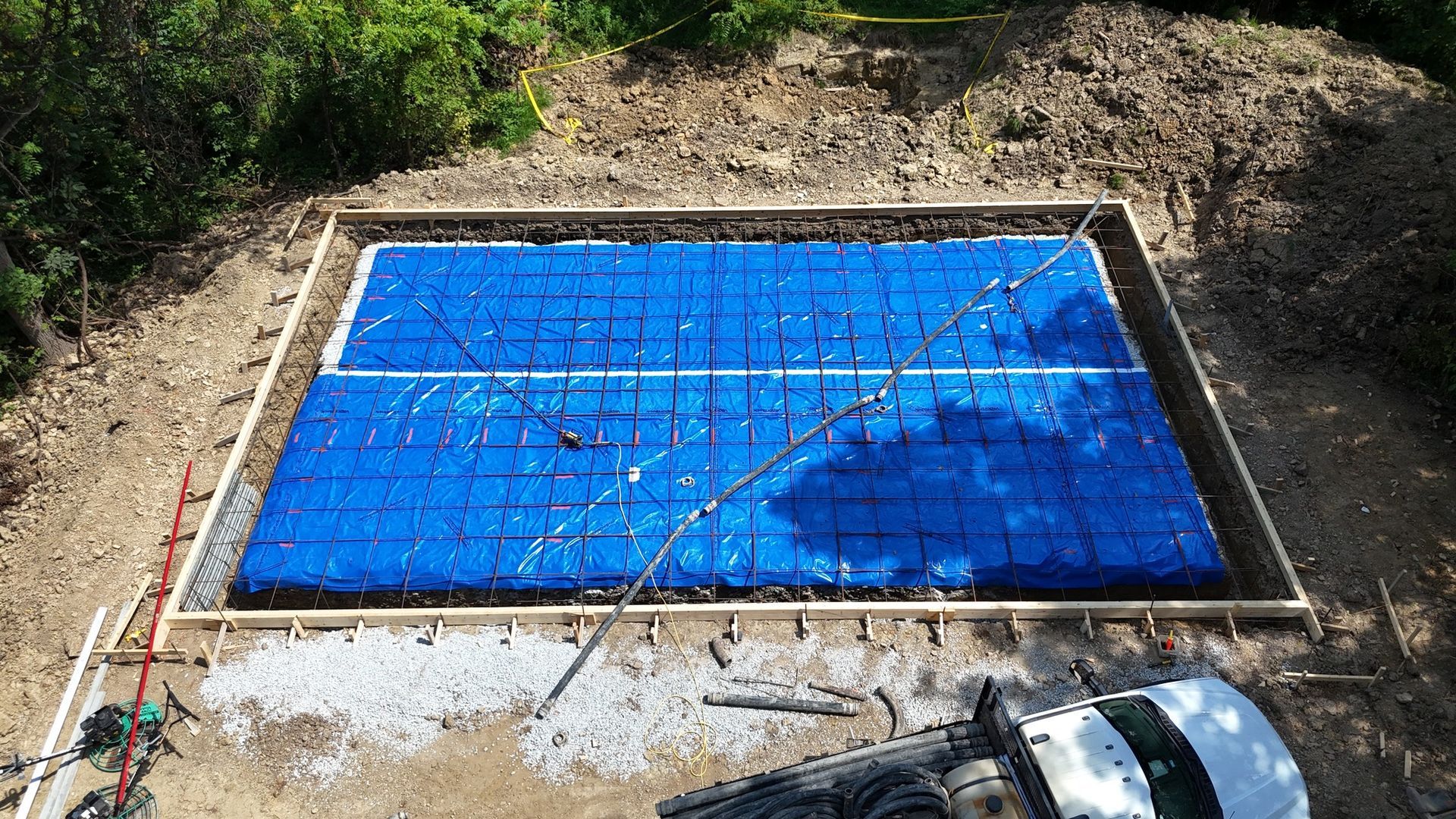Construction site with blue drainage cells inside a rectangular wooden frame.