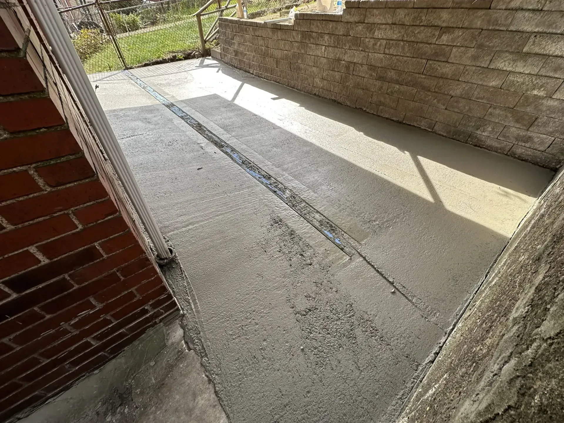 Freshly poured concrete patio with a long, recessed drainage channel.