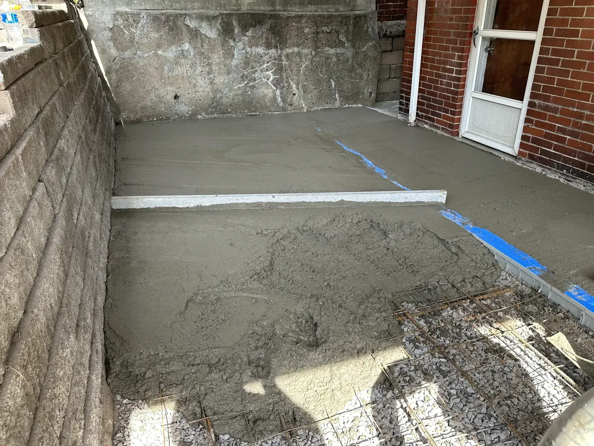 Freshly poured concrete patio; a level is placed across the surface, ready for smoothing.