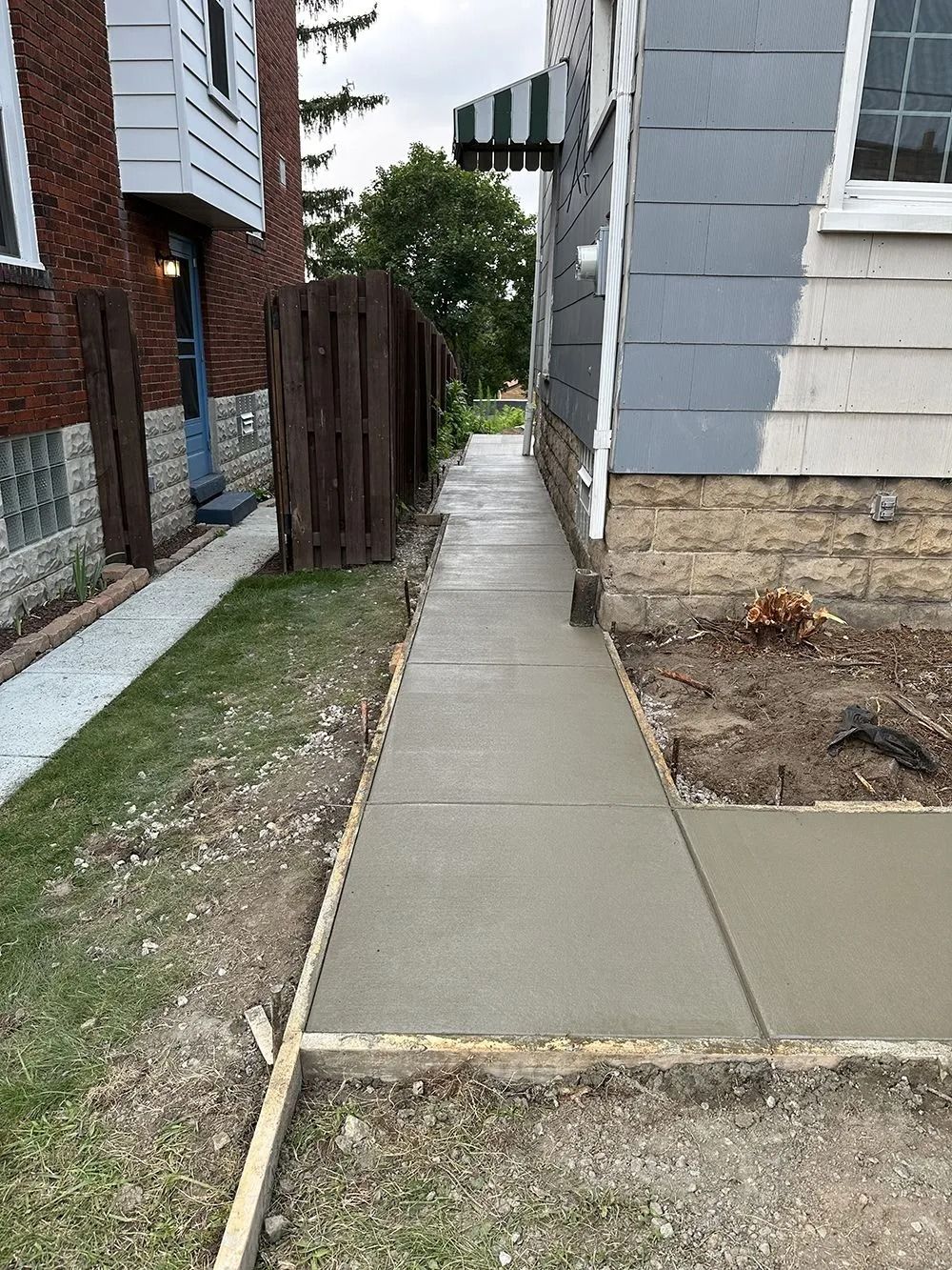 Freshly poured concrete sidewalk next to a building and grass.