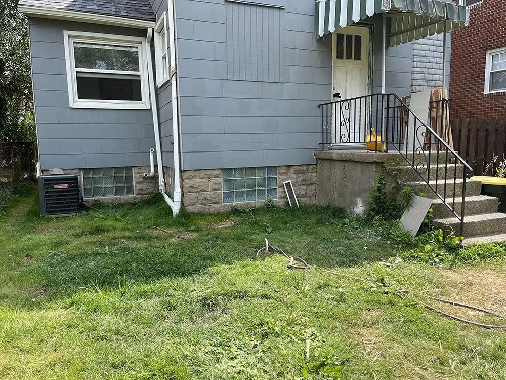 Exterior of a blue house with grass and stairs leading to the front door.