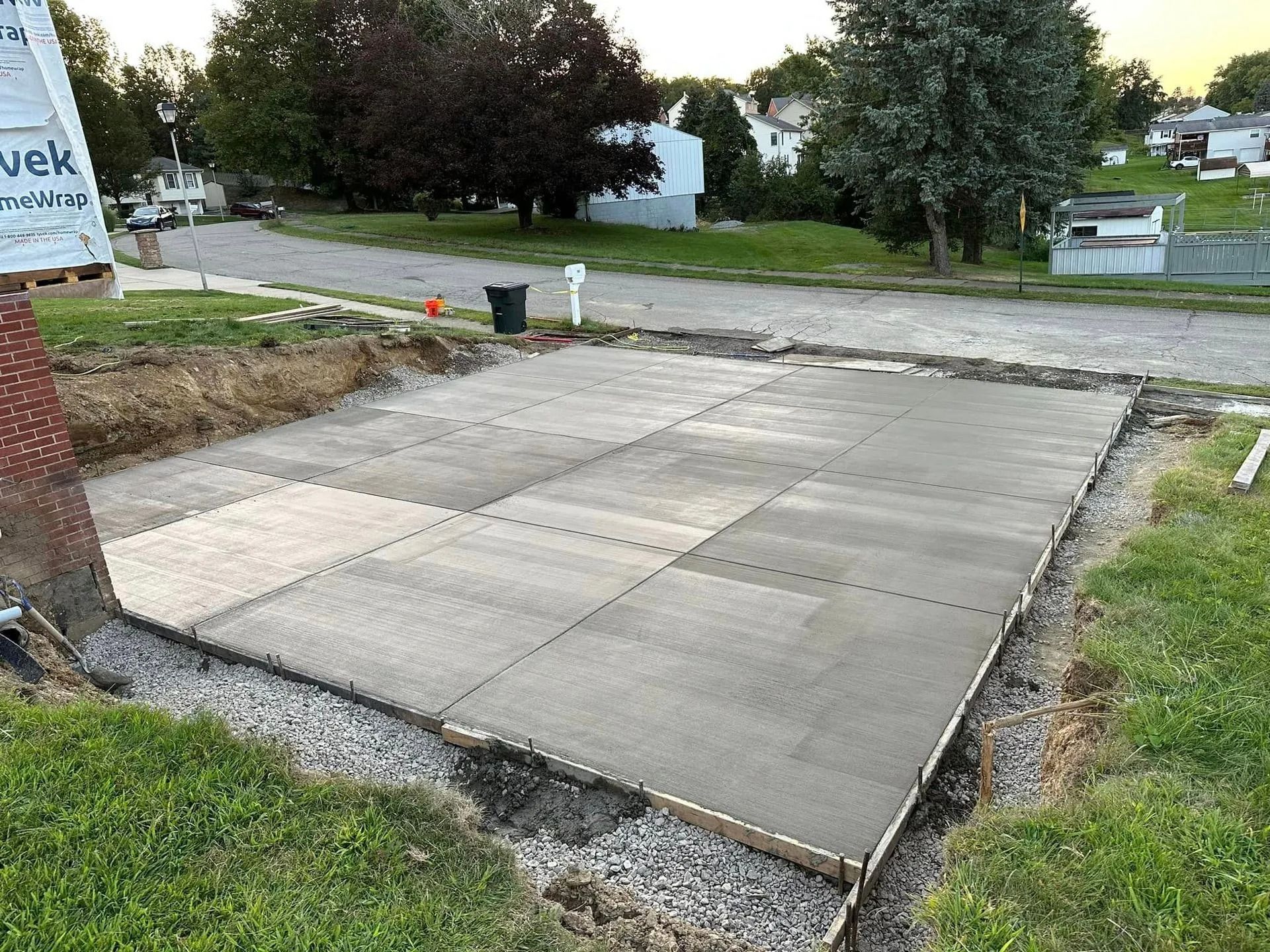Concrete patio under construction, enclosed by wood frame and surrounded by gravel and grass.