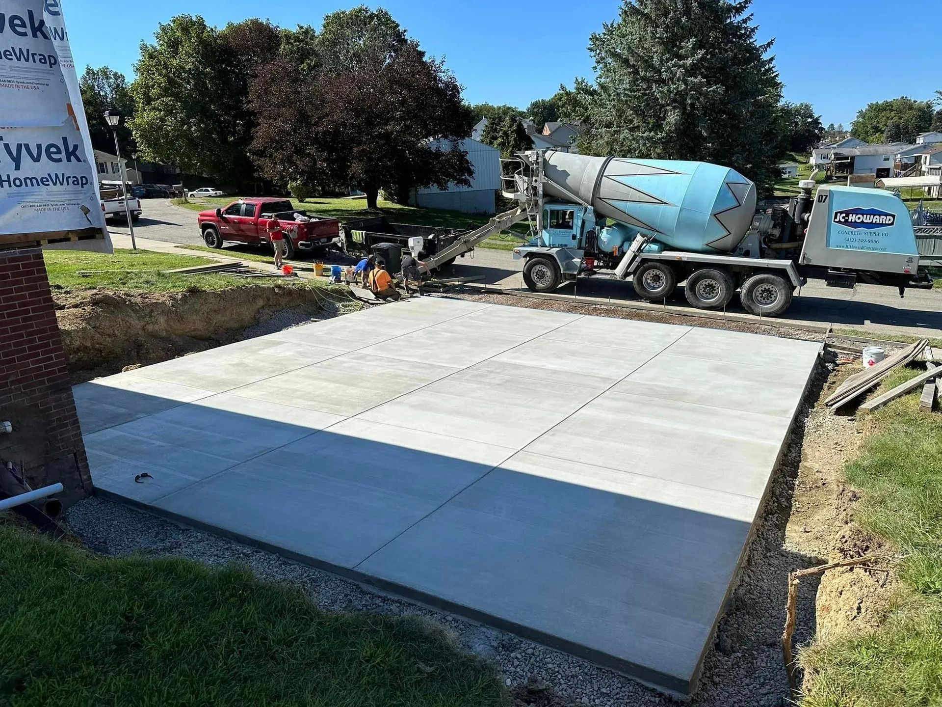 Freshly poured concrete slab being filled by a cement truck on a construction site.