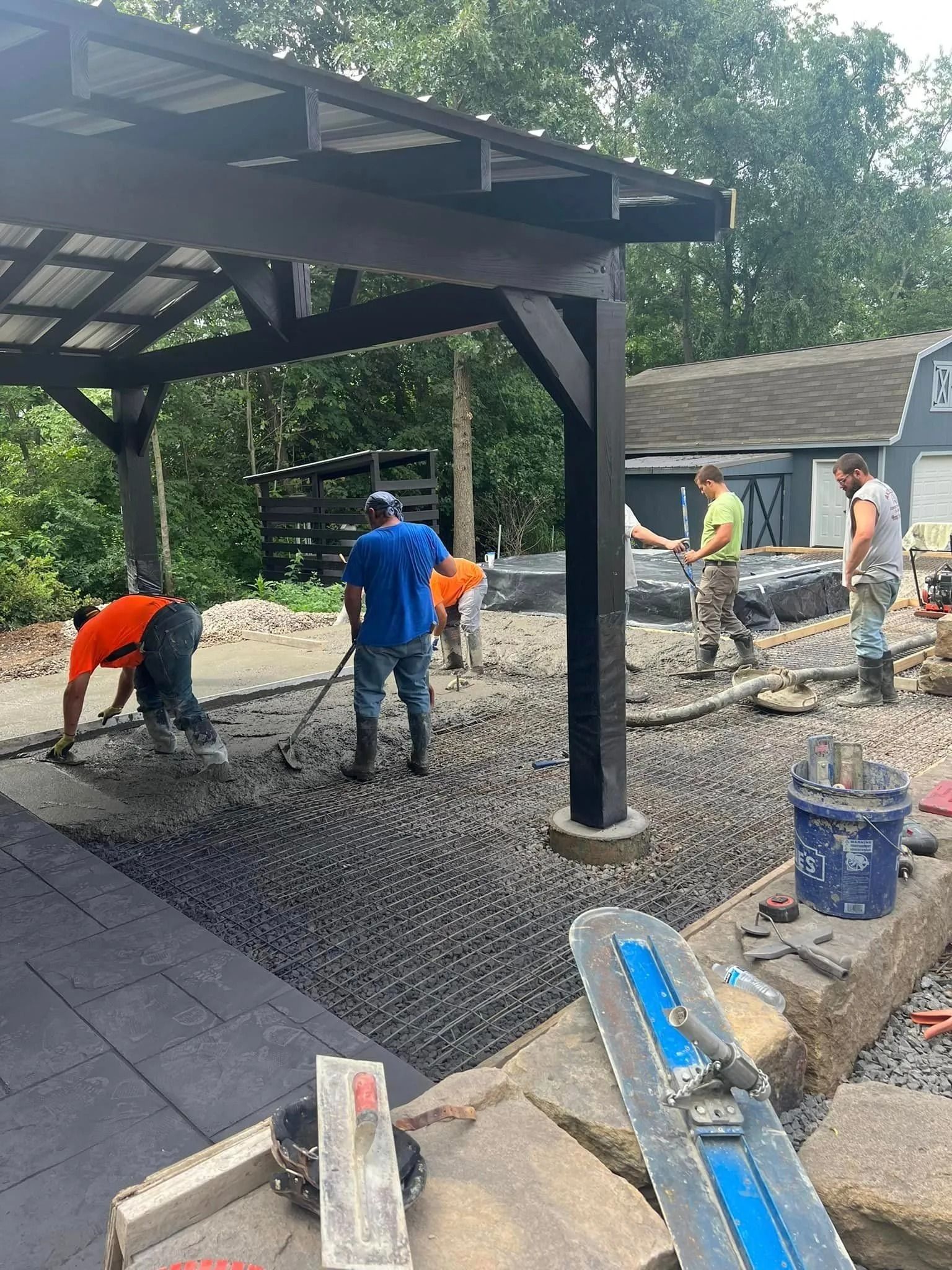 Construction workers pouring concrete under a pergola.
