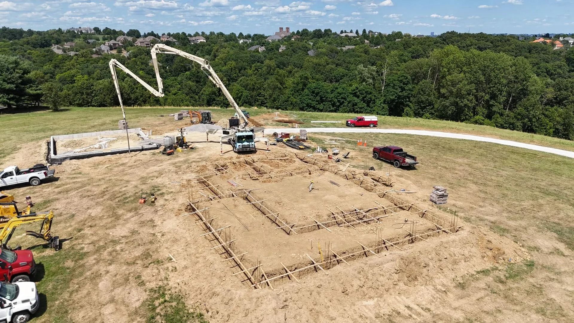 Construction site with concrete pump truck pouring concrete into foundation forms.