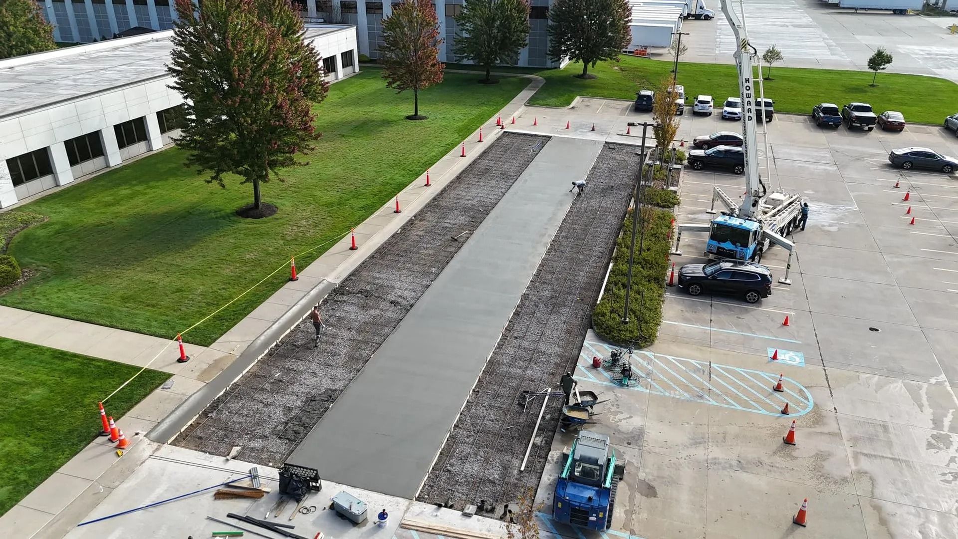 Construction of a concrete walkway next to a building. A concrete truck pours concrete.
