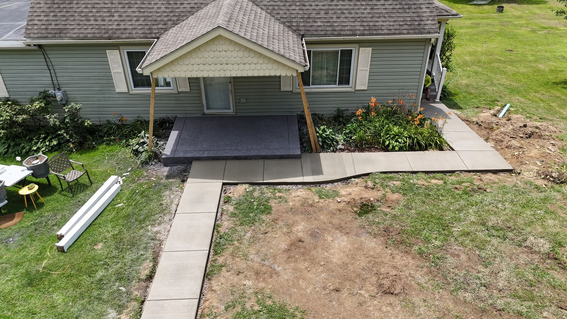 Green house with porch and concrete walkway.