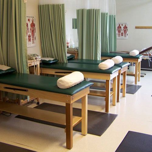 Physical therapy room with treatment tables and privacy curtains.