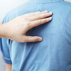 Hand on a blue shirt, touching the back.