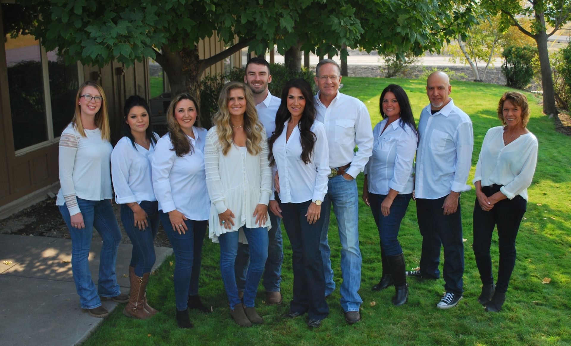 Group of ten people in white shirts and jeans, posing outdoors.