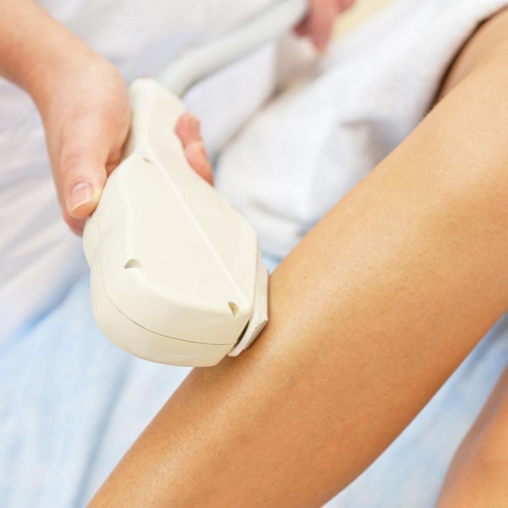 A woman is getting a hair removal treatment on her leg