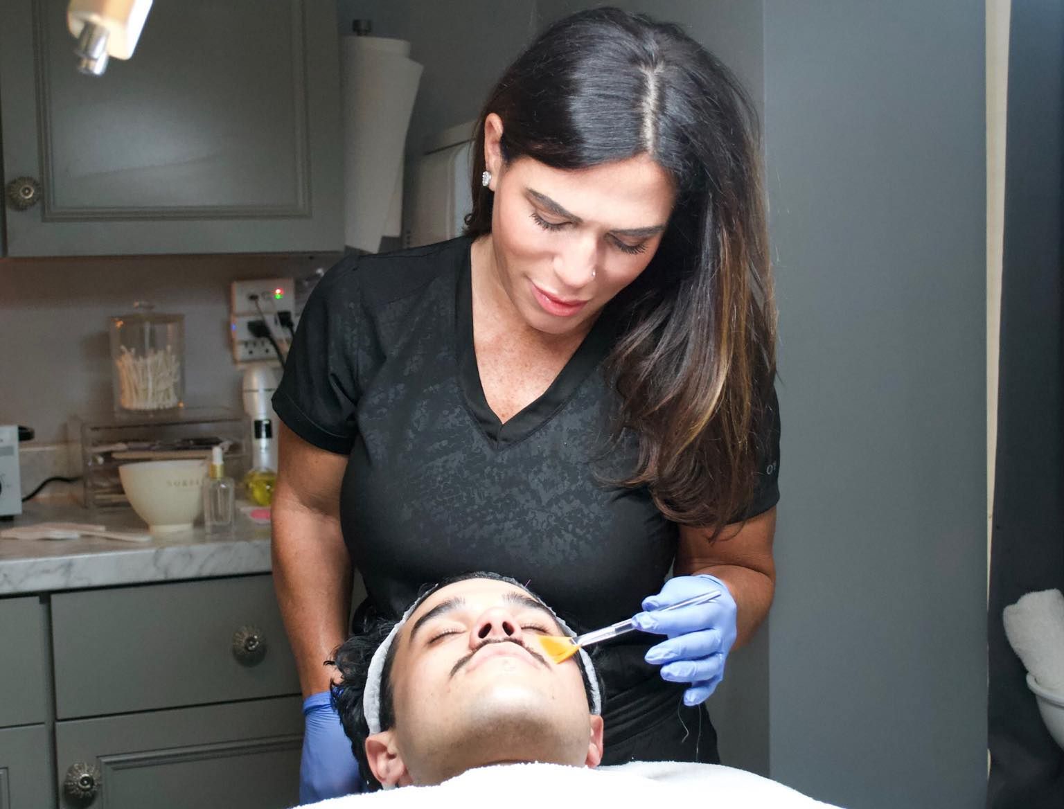 A woman is applying a facial treatment to a man's face.