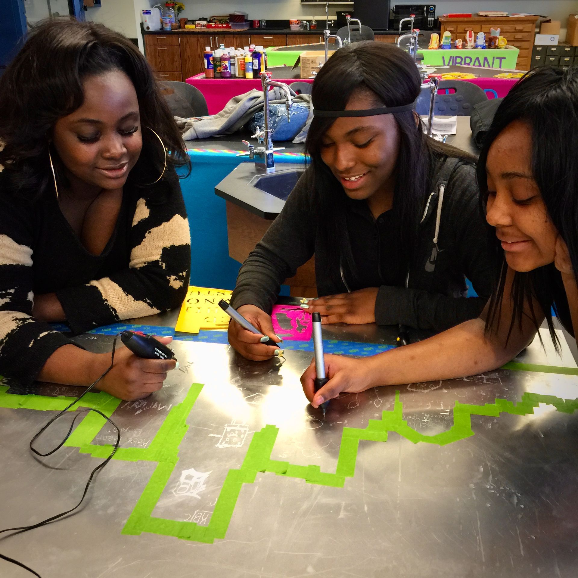 Three women sit at a table with a sign that says modant on it