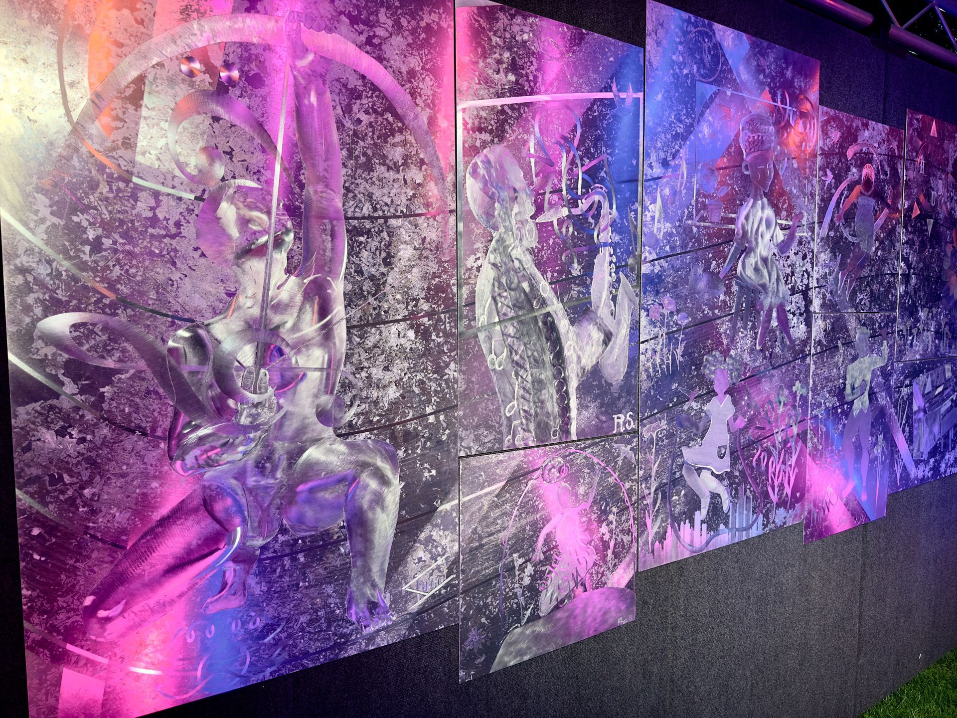 A large painting on a wall with purple lights behind it.