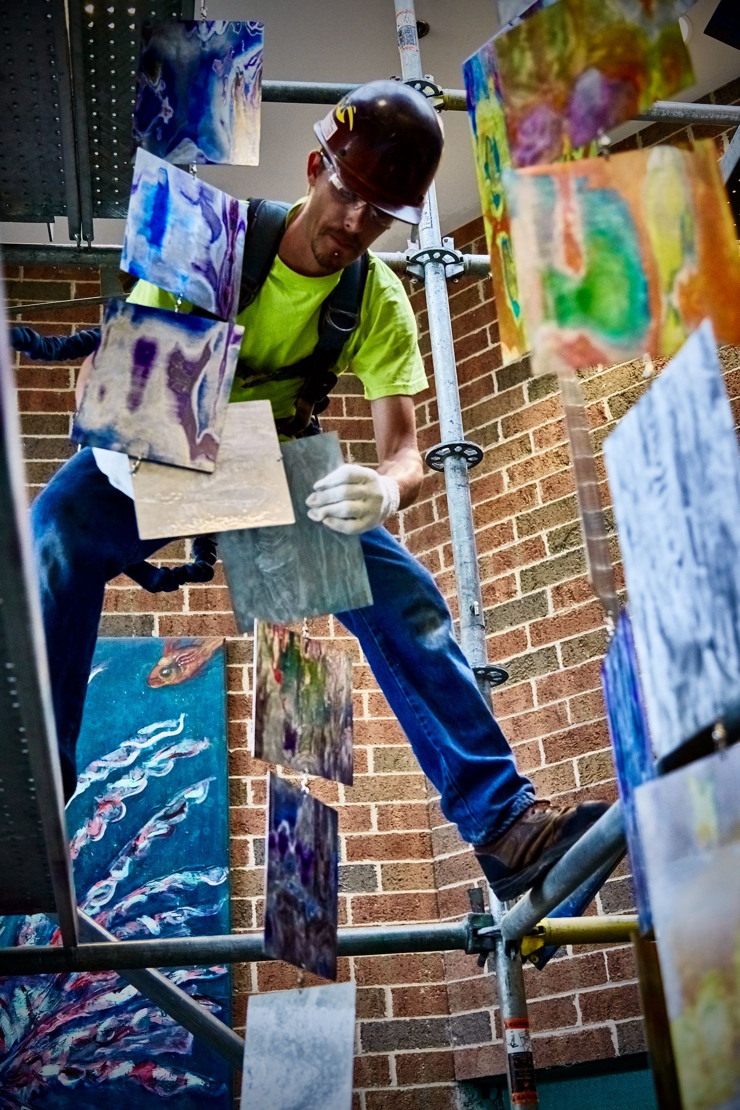 A man is sitting on a scaffolding holding a piece of wood.