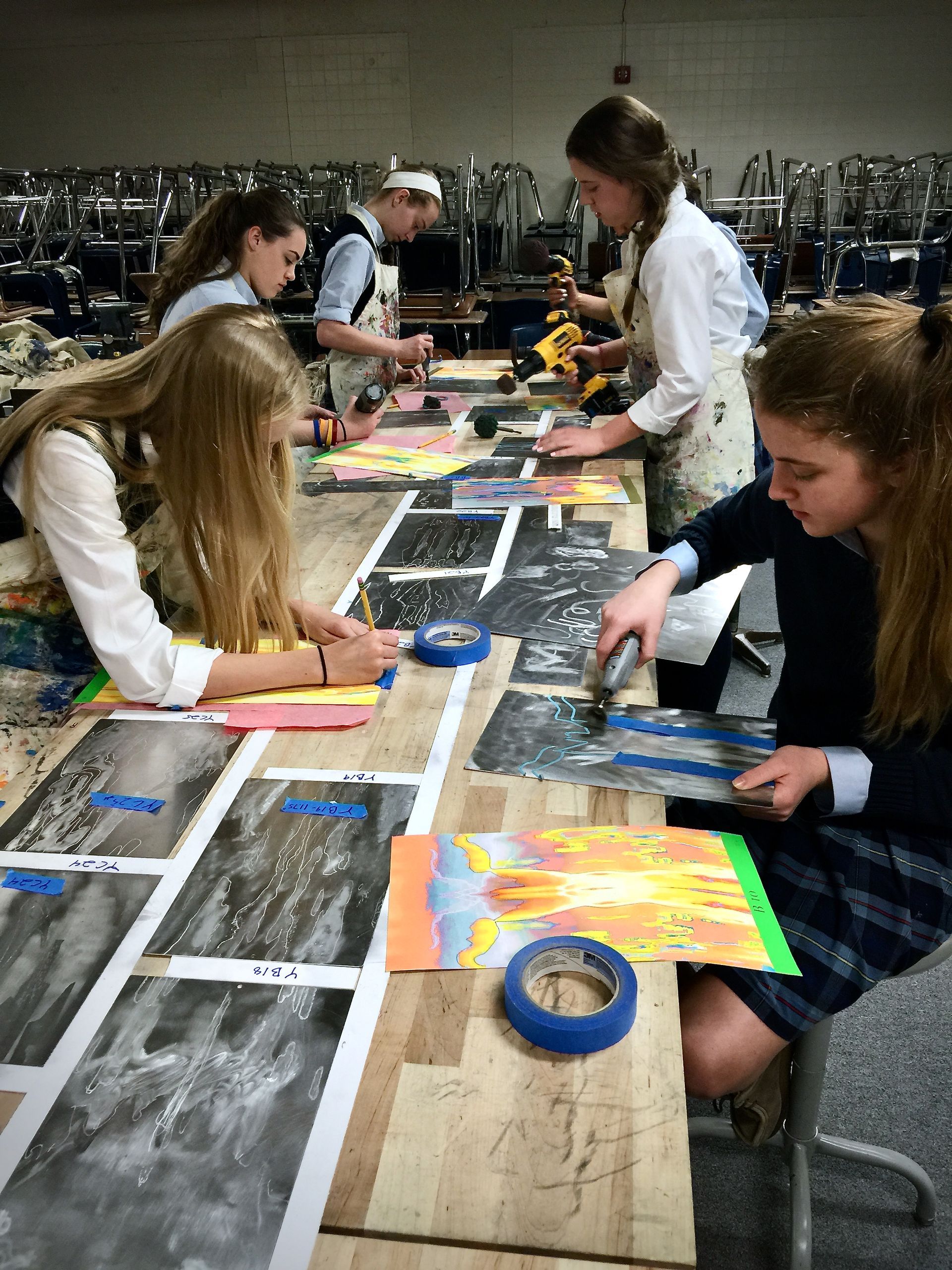 A group of young girls are sitting at a table painting.