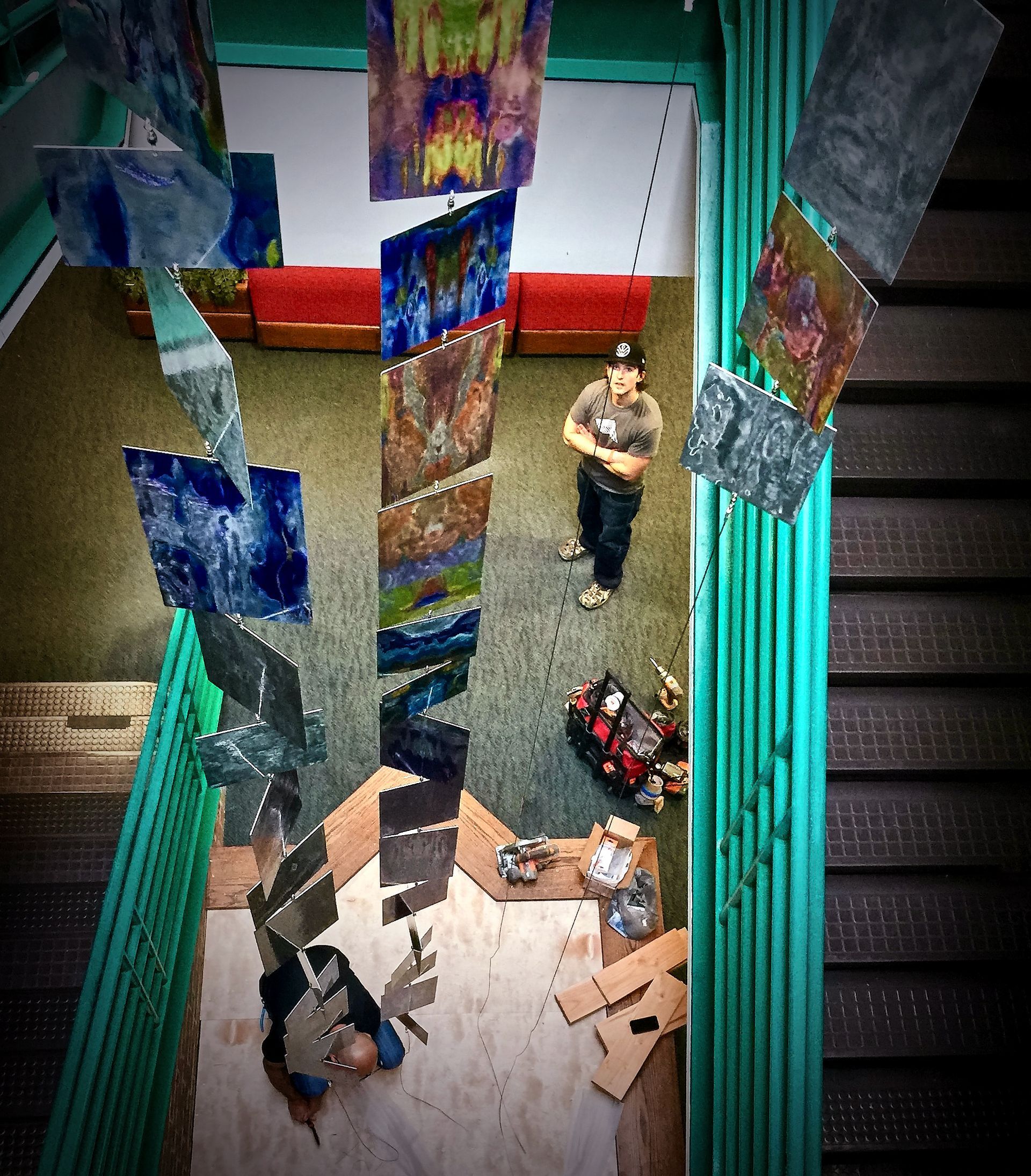 An aerial view of a room with paintings hanging from the ceiling