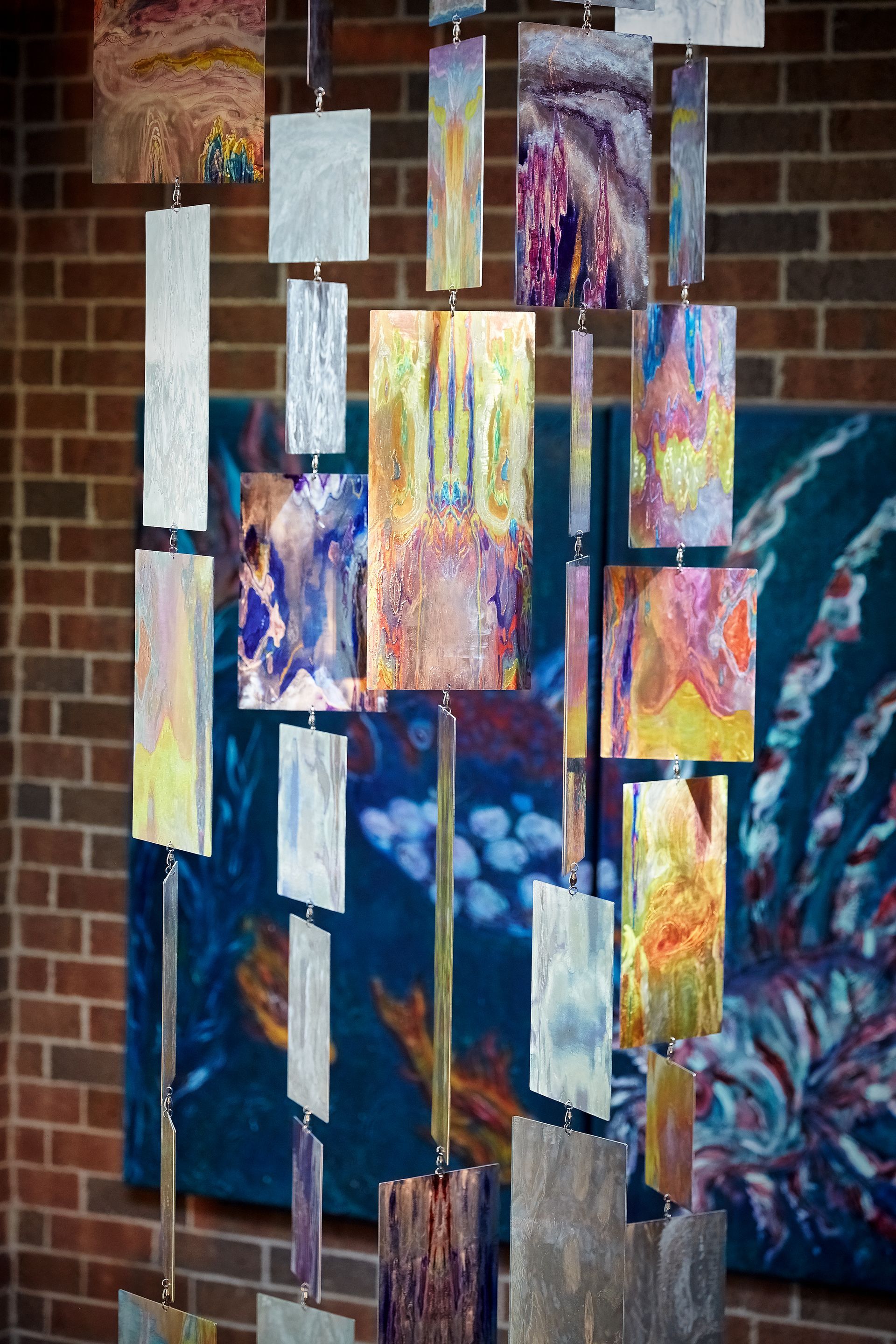 A painting is hanging on a wall next to a brick wall.