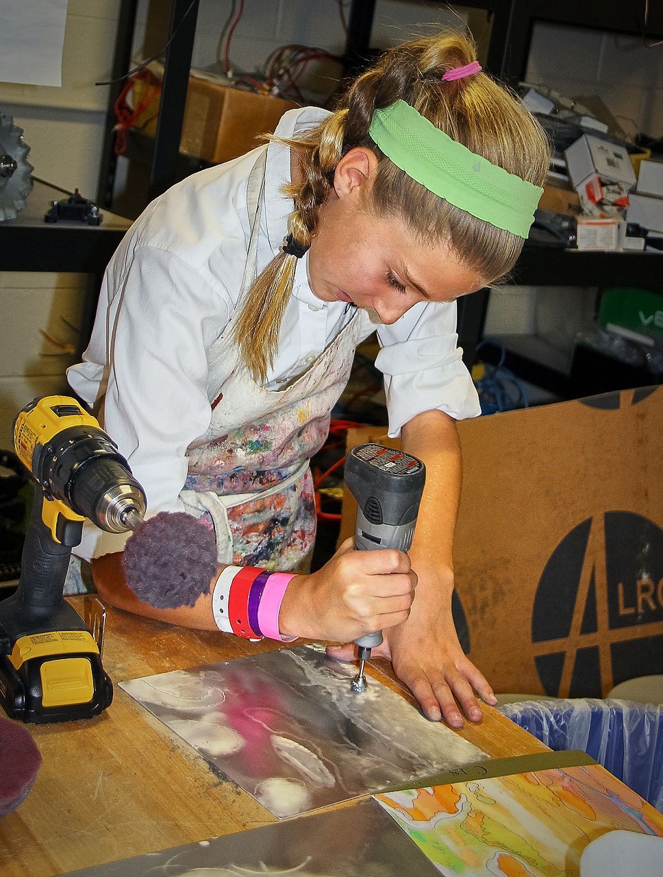 A girl wearing a green headband is using a drill