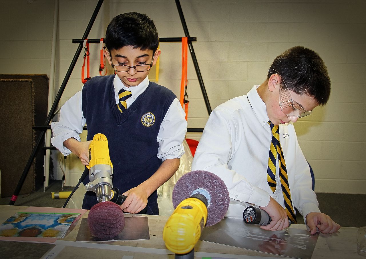 Two young boys are working on a project with tools