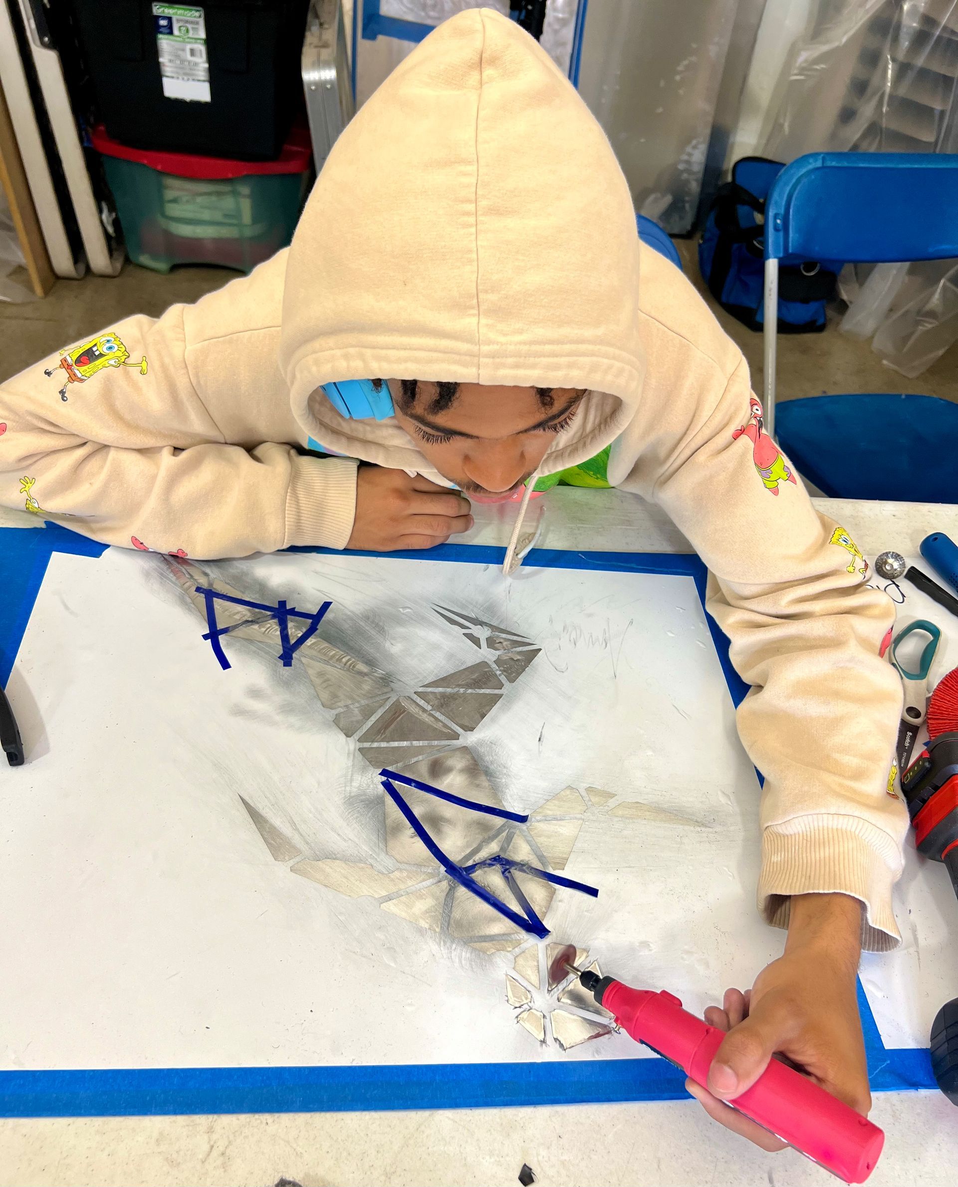 A person in a hoodie is drawing on a piece of paper.