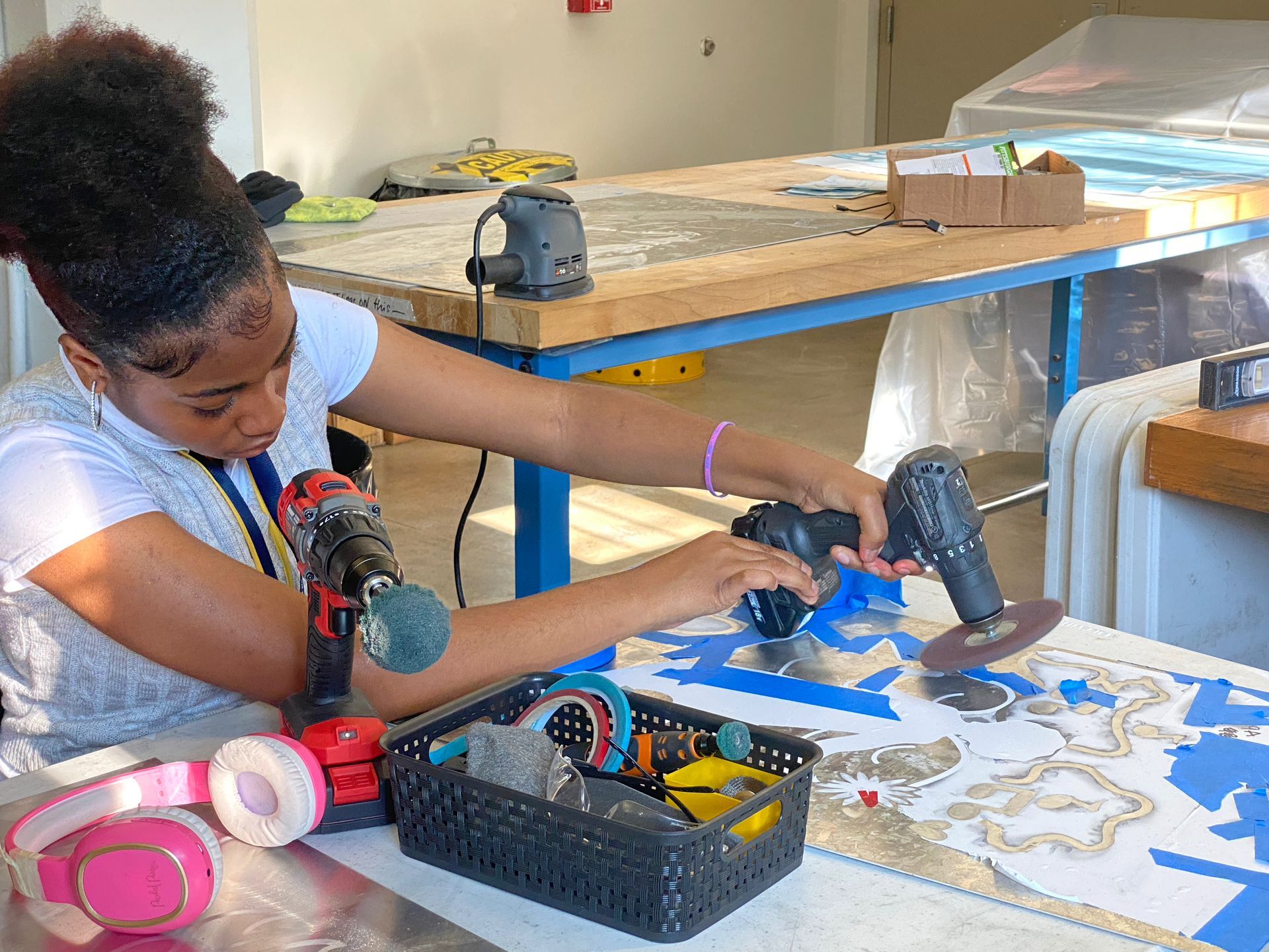 A young girl is using a drill on a table.