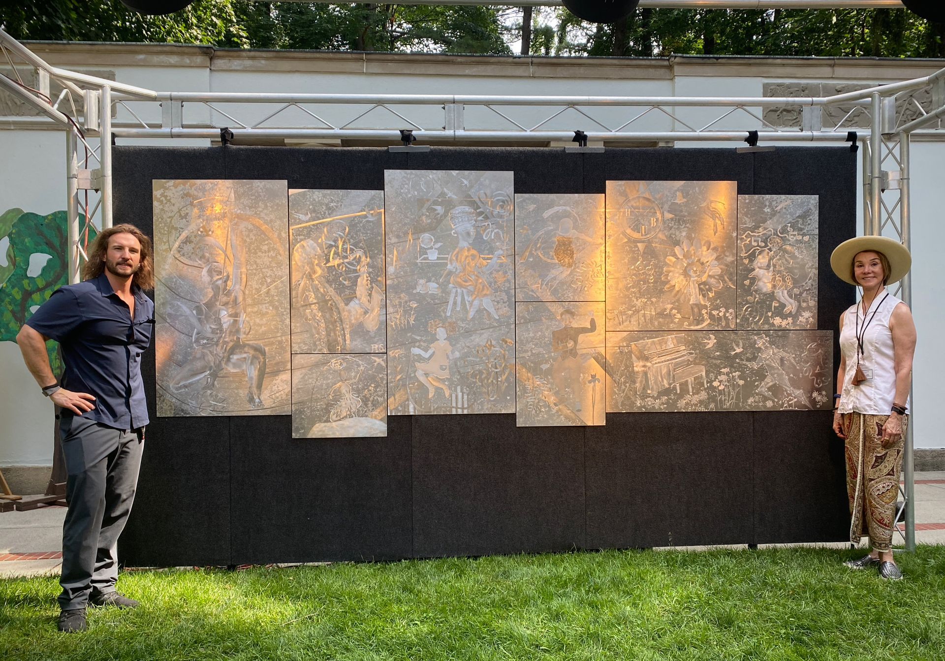 A man and a woman are standing in front of a large painting.