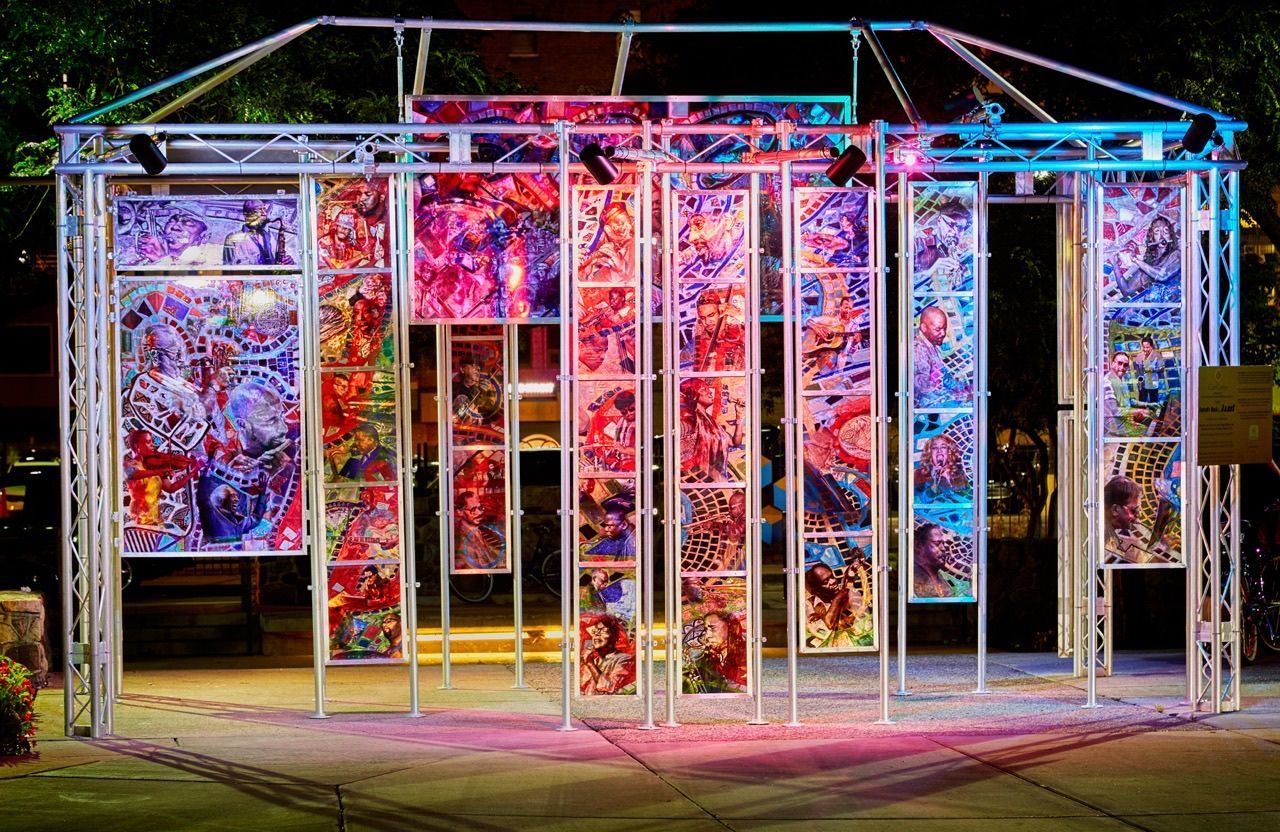 A large structure with a lot of paintings on it is lit up at night.