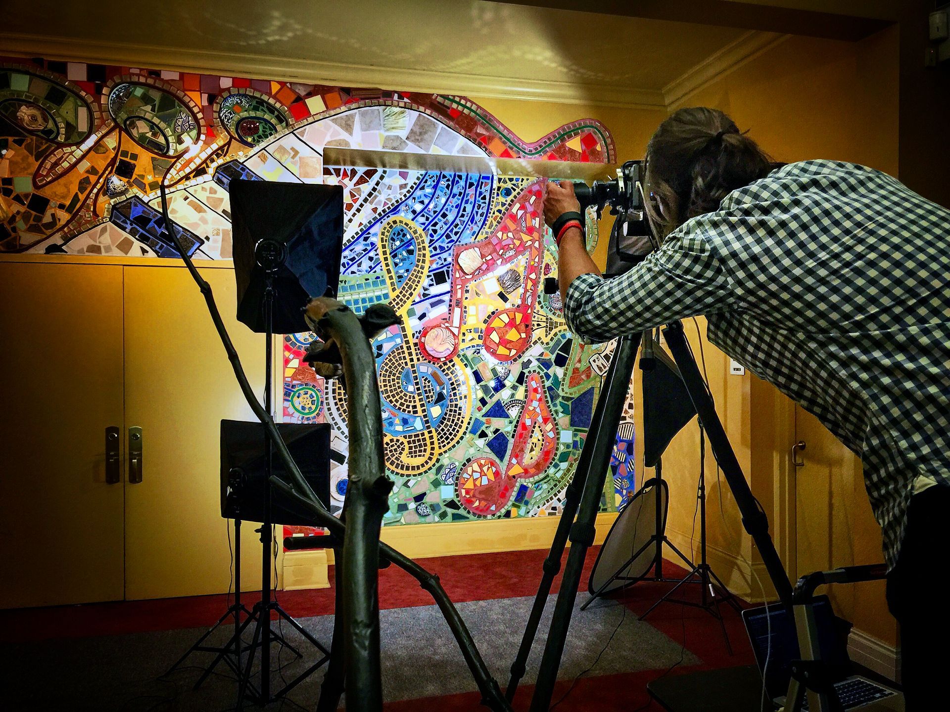 A man is taking a picture of a painting on a wall