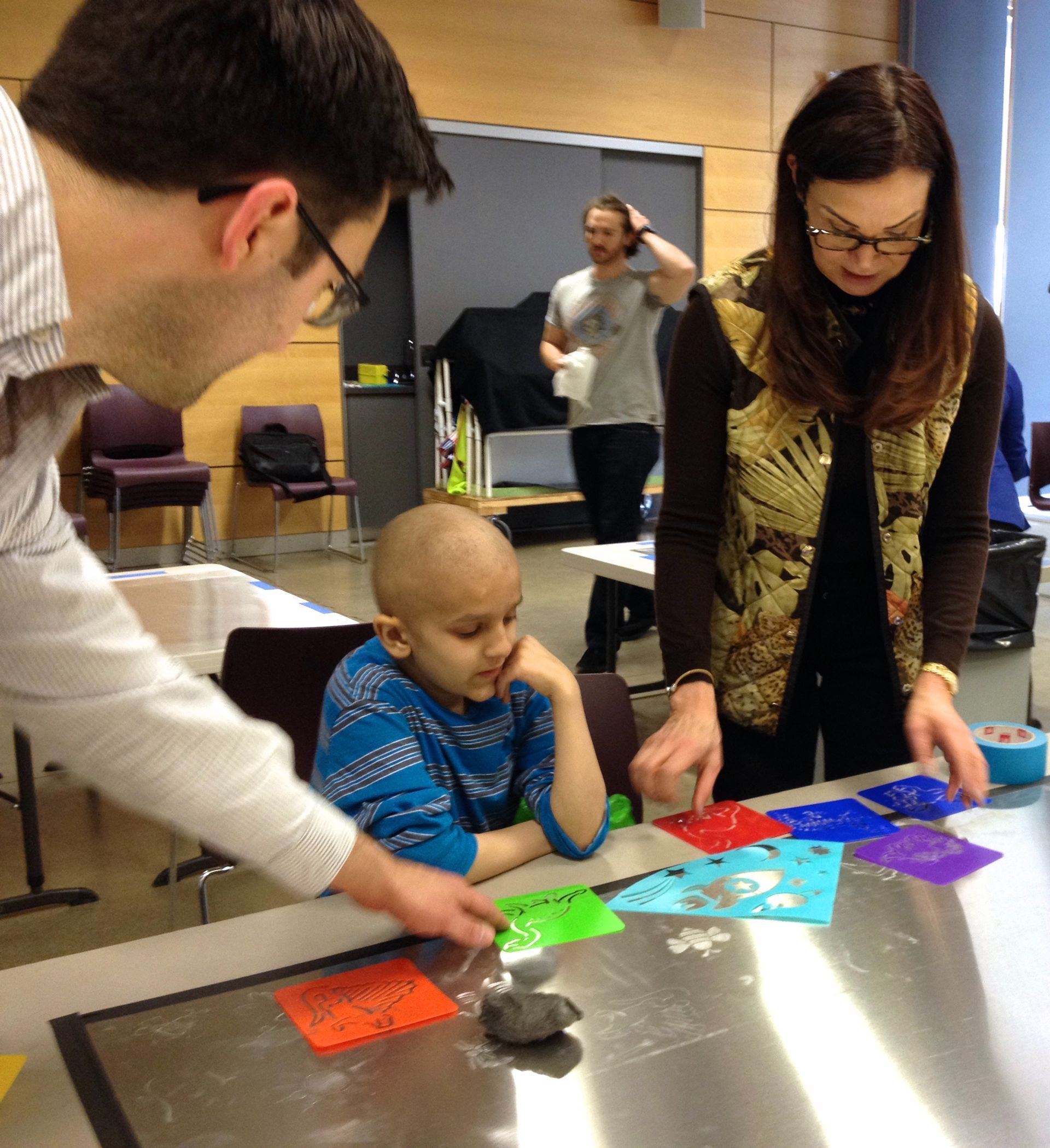A man and a woman are looking at a child sitting at a table